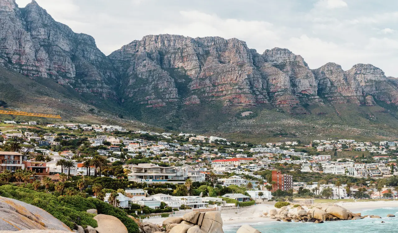 Panoramic view of Camps Bay properties below the Twelve Apostles mountains, illustrating the area affected by Cape Town height restrictions.